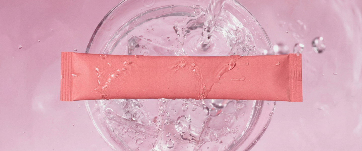 Electrolyte drink sachet with hyaluronic acid and collagen peptides over ice water.