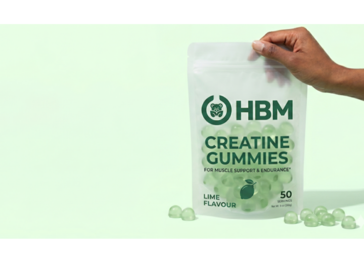 On the right, a person's hand holds a frosted semi-transparent stand-up pouch featuring the dark green HBM logo. The pouch is filled with clear, light green dome-shaped gummies and labeled "CREATINE GUMMIES" and "LIME FLAVOUR" indicating fast nutraceutical launches